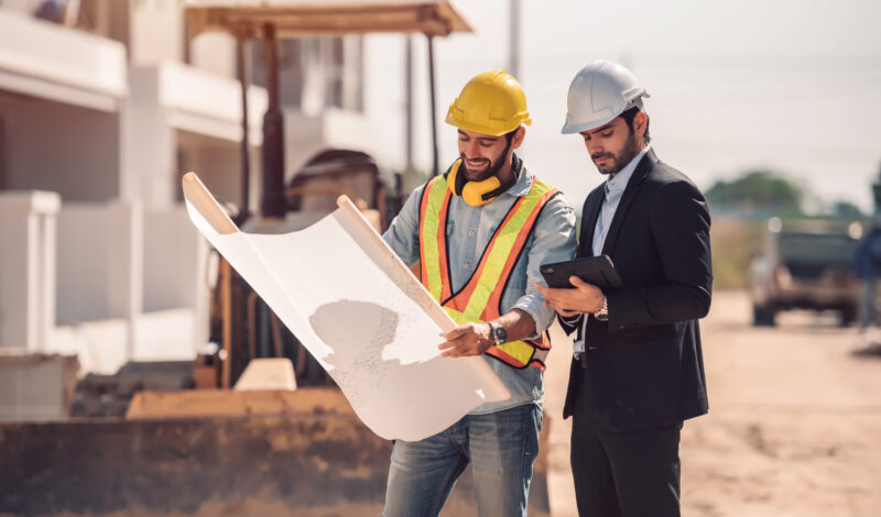 civil-engineer-construction-worker-manager-holding-digital-tablet-blueprints-talking-planing-about-construction-site-cooperation-teamwork-concept