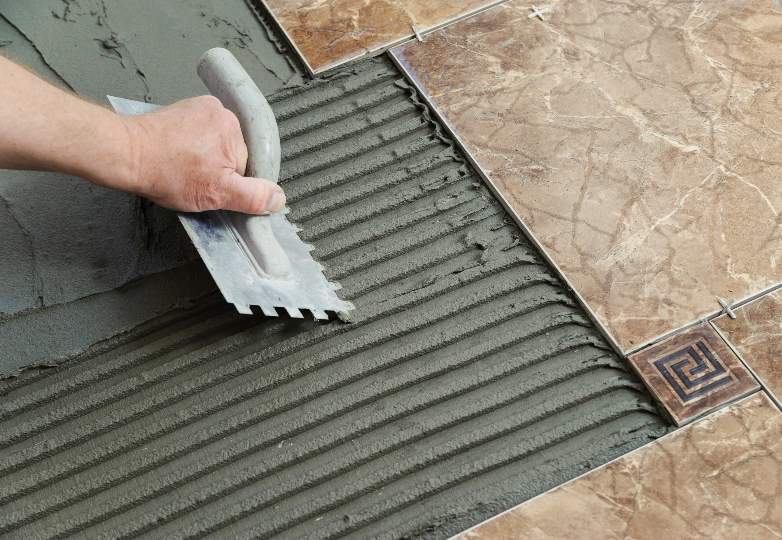 laying-ceramic-tiles-troweling-adhesive-onto-concrete-floor-preparation-laying-white-floor-tile